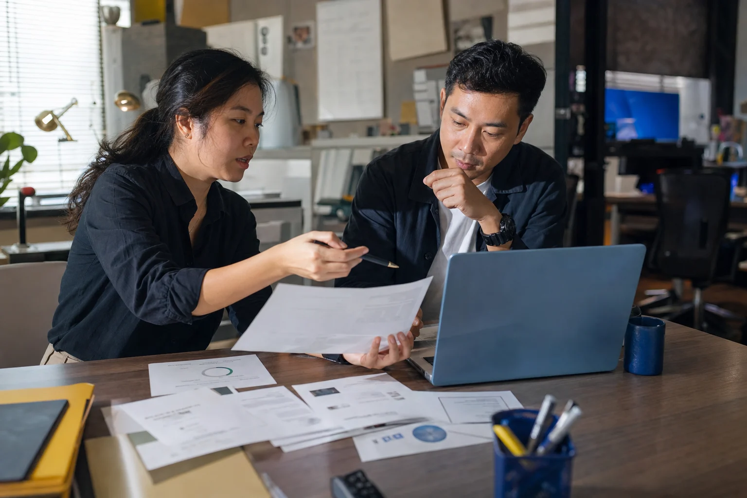 Two recruiting leads reviewing candidate evidence at a working operations desk.